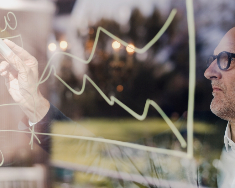 Ein Mann zeichnet ein Diagramm auf eine Glasscheibe