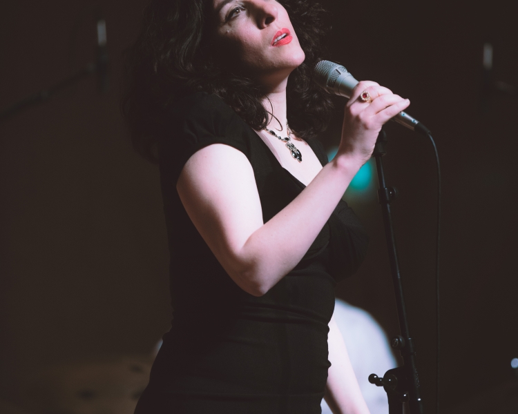 Eine Frau in schwarzem Kleid singt auf einer Bühne