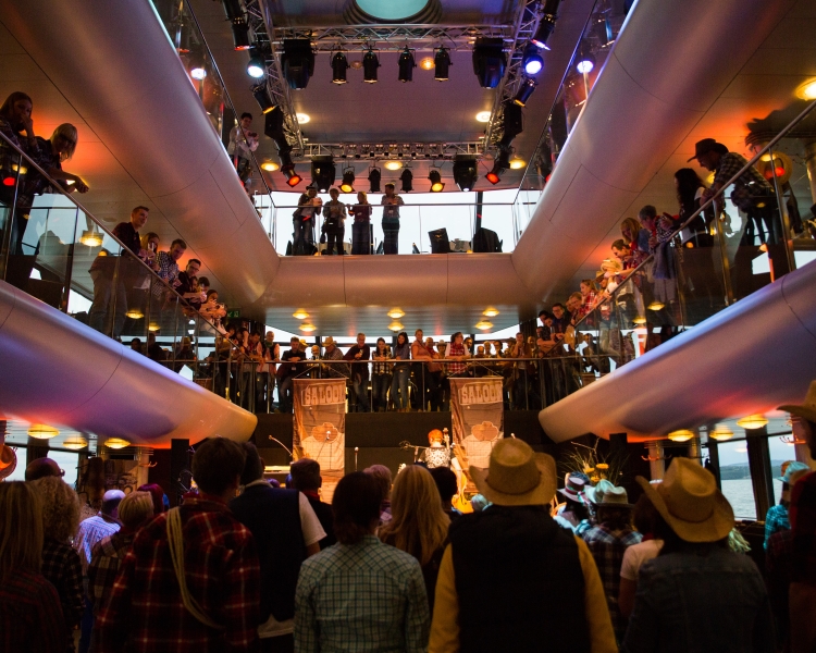 Zweistöckige Event-Location mit Personen, die auf eine Veranstaltung in der Mitte des Raumes blicken