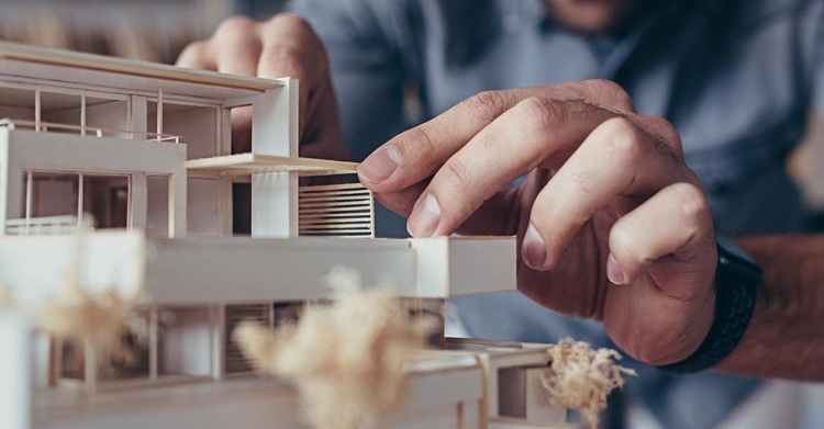 A person works on a wood house model