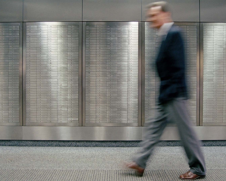 A business man walks by lockers in a bank institute