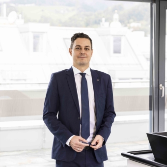 Ein Mann lächelt in die Kamera und hält einen Stift in der Hand