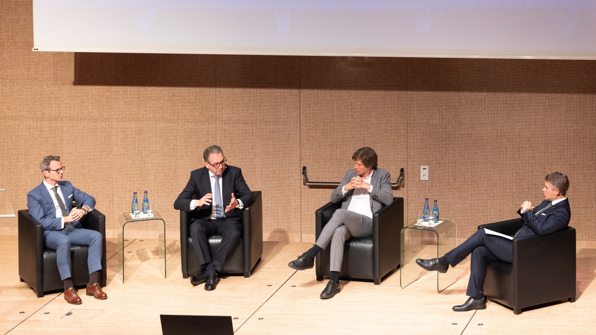 4 Männer sitzen auf einer Bühne und unterhalten sich