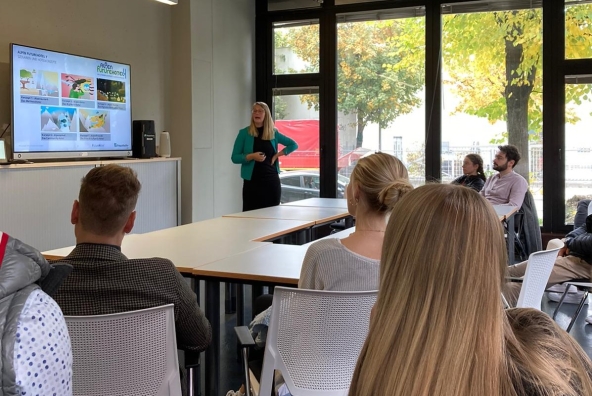 Eine Frau präsentiert einer Gruppe Personen etwas