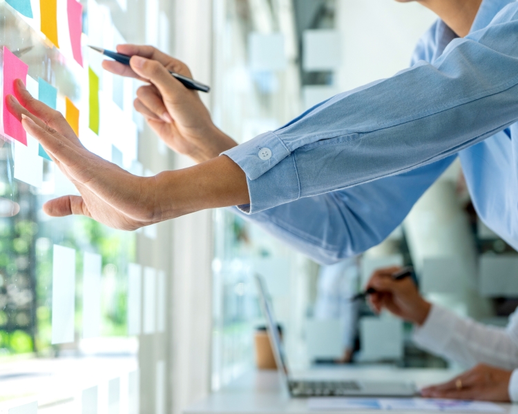 Eine Frau schreibt auf Post its, die auf einer Scheibe kleben