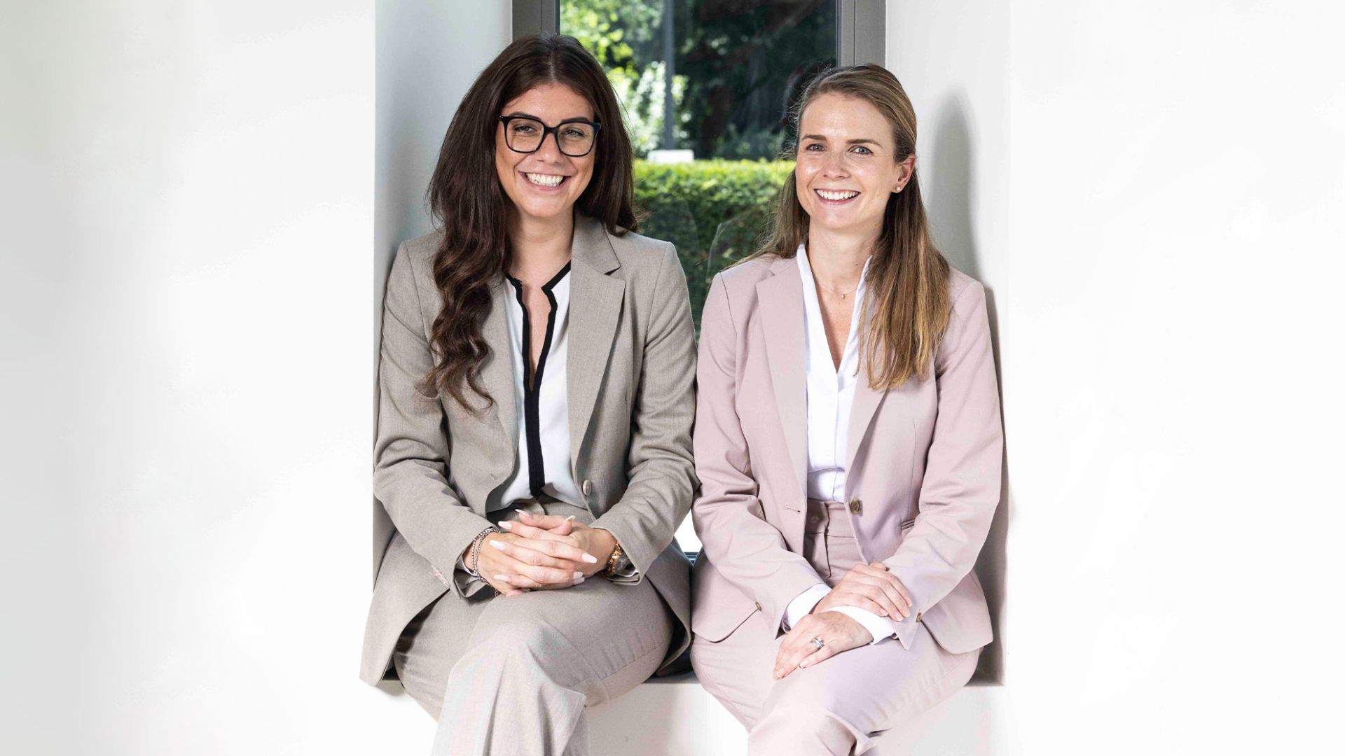 2 Frauen in einem hellen Anzug sehen in die Kamera