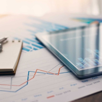 Ein Tablet liegt auf einem Tisch inklusiv Finanzdokumente