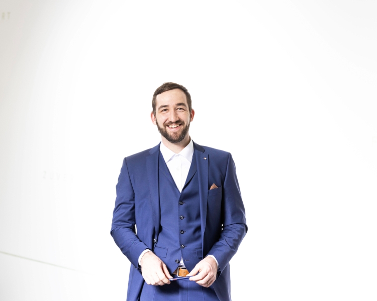 Ein Mann in einem blauen Anzug lächelt in die Kamera