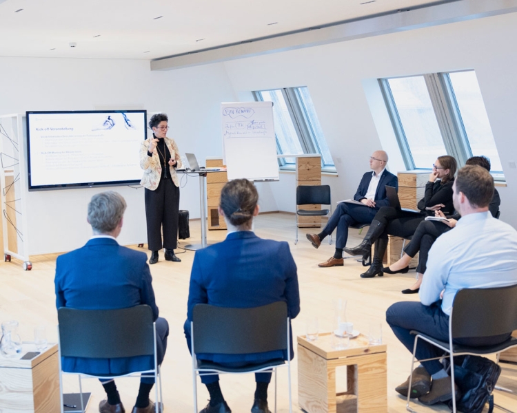 Mehrere BTV Mitarbeiter*innen betrachten eine Person, die eine Präsentation mit großem Bildschirm hält