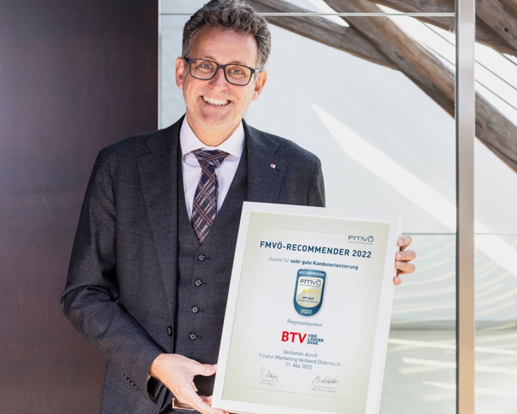 Gerhard Burtscher im Anzug hält die eingerahmte Auszeichnung FMVÖ-Recommender 2022 in den Händen