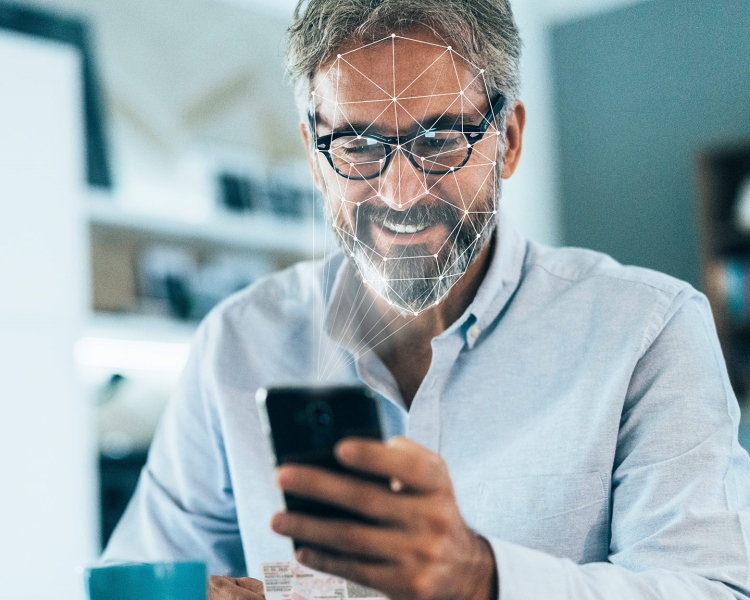 Ein Mann blickt auf sein Smartphone, um sich via Gesichtserkennung anzumelden