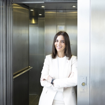 Eine Frau in weißen Klamotten steht vor einem Aufzug