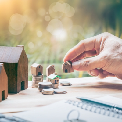 Mann stellt ein Miniatur-Haus auf den Tisch neben andere Miniatur-Häuser
