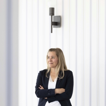 Anja Mell, Mitarbeiterin BTV Stuttgart vor einer gestreiften Tapete.