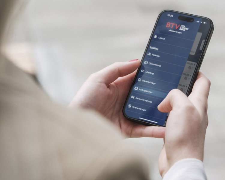 Eine Frau hält ihr Handy in der Hand und schaut in ihr Internetbanking.