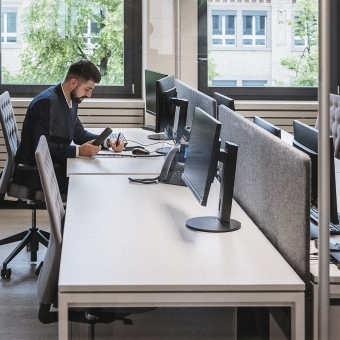 Ein Mann in Anzug sitzt am Schreibtisch und notiert etwas.