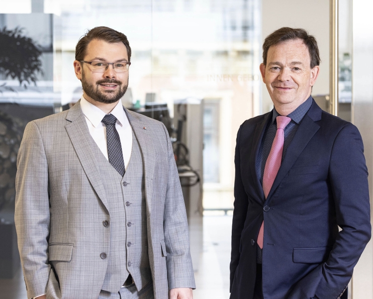 Benjamin Telser und Georg Lehmann im Anzug vor einer Glaswand in einem Büro