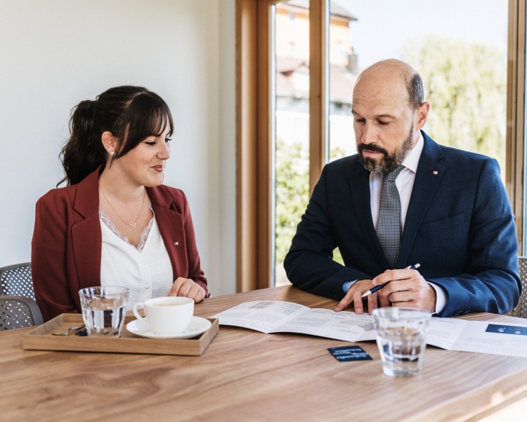 Zwei Männer im Anzug unterhalten sich an einem Esstisch.