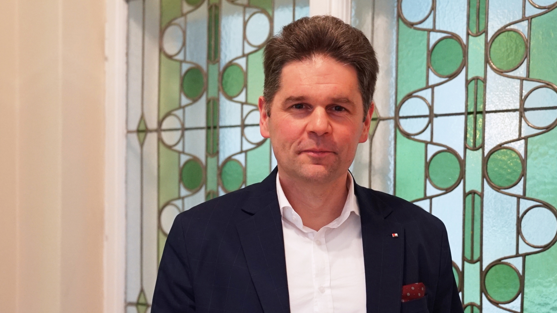 Ein Mann in einem Anzug steht vor einem Fenster