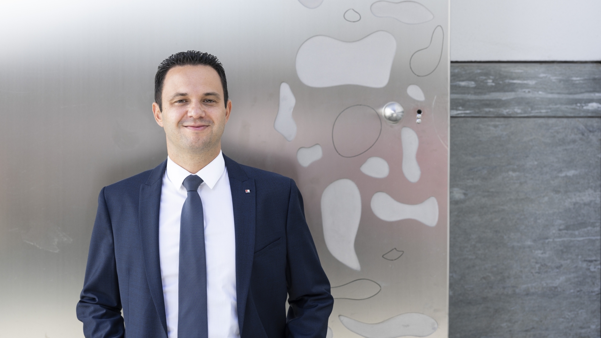 Ein Mann steht vor einem Gebäude und trägt einen blauen Anzug