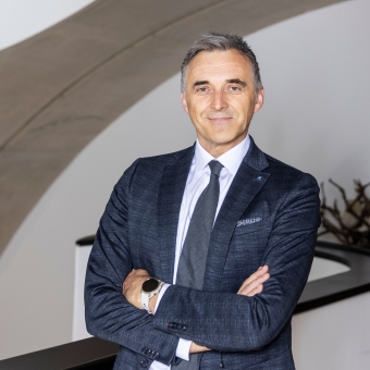 Ein Mann mit blau kariertem Anzug und weißem Hemd lächelt in die Kamera