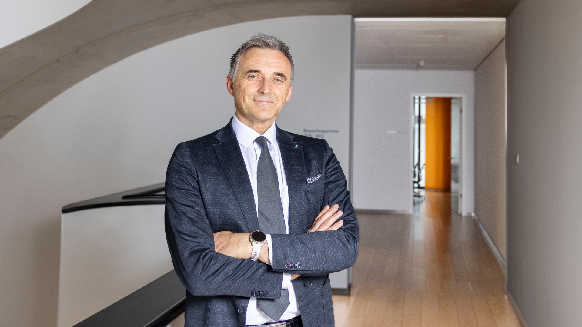 Ein Mann mit blau kariertem Anzug und weißem Hemd lächelt in die Kamera