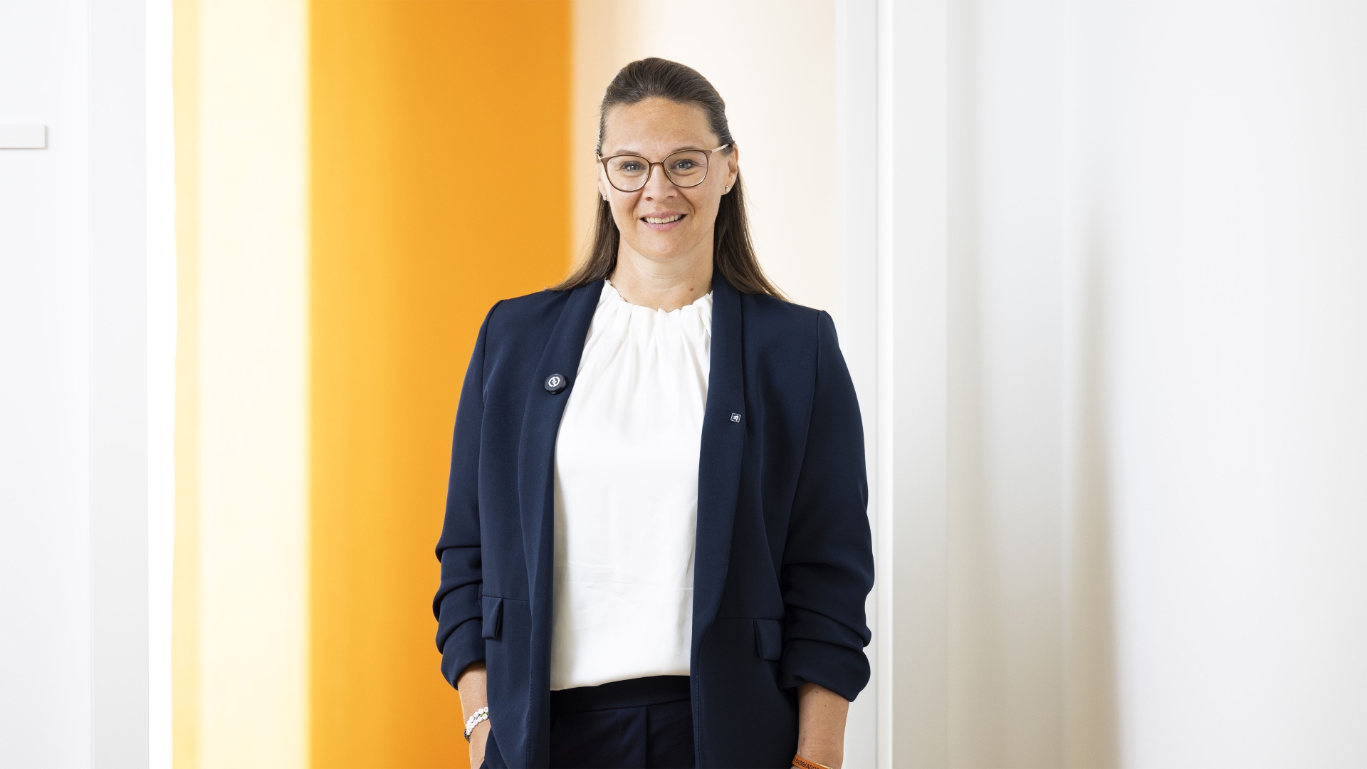 Ein Frau steht in einer Türöffnung und trägt einen blauen Blazer