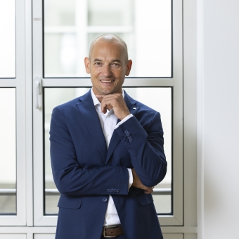 Ein Mann in einem blauen Anzug steht vor einem Fenster