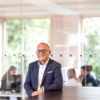 Ein Mann steht an einem Stehtisch und trägt eine Brille