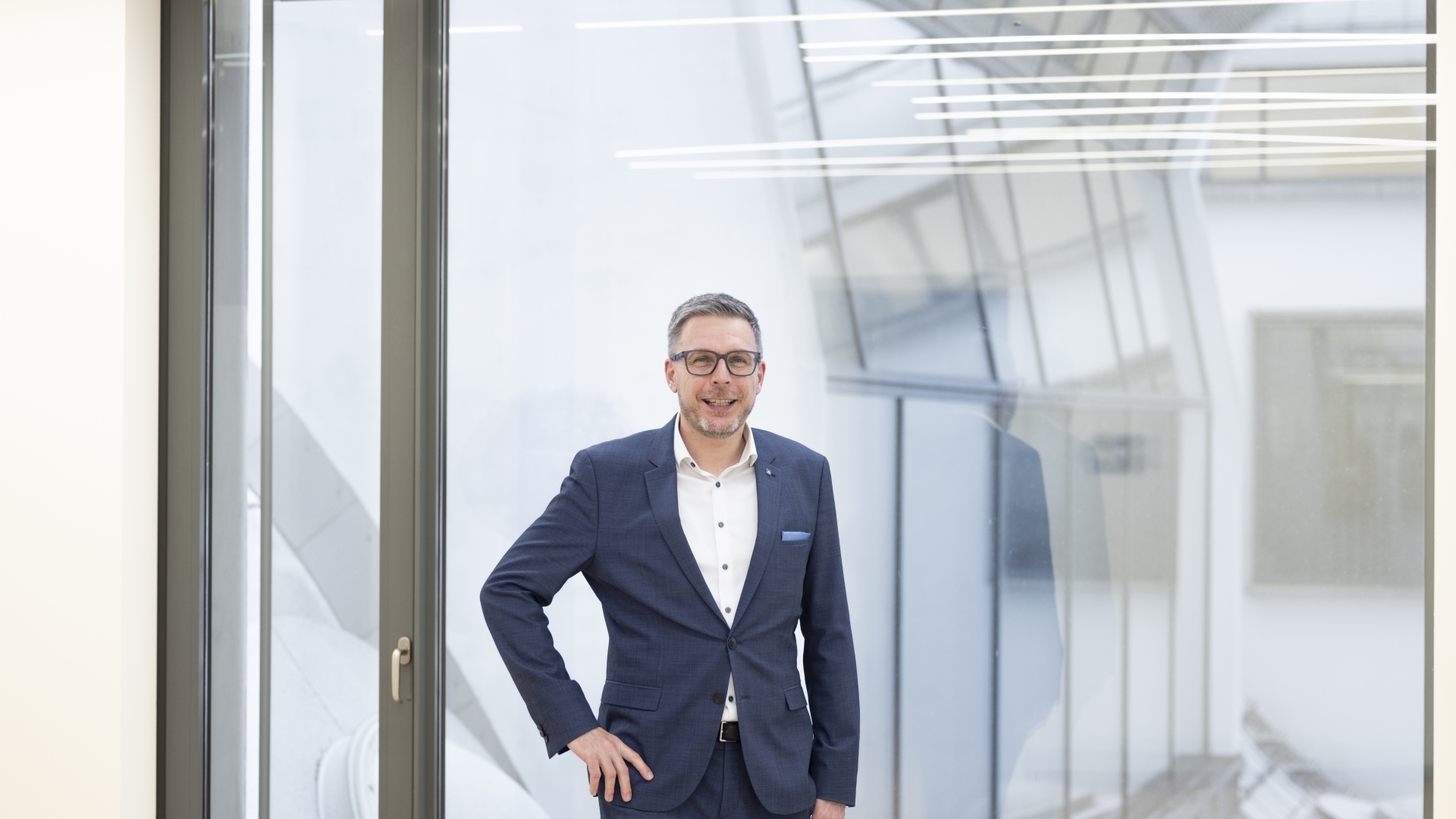 Simon Knittel, Experte für Corporate & International Finance bei der BTV Vier Länder Bank, trägt einen blauen Anzug und steht in einer Bankfiliale.