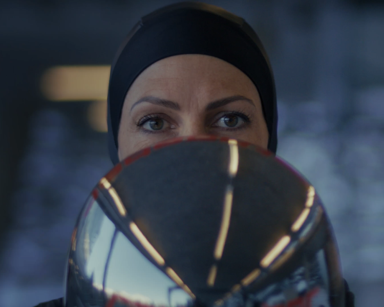 Janine Flock hält ihren Rennhelm und blickt in die Kamera