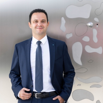 Mario Scherl im blauen Anzug vor der Eingangstüre der BTV Stadtforum in Innsbruck