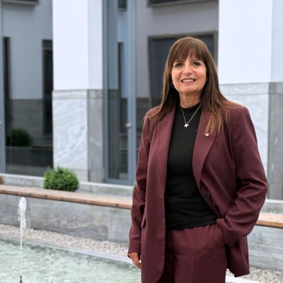 Claudia Gruber, Teilnehmerin des BTV Female Spirit, steht im Innenhof der BTV‑Filiale Innsbruck und trägt einen weinroten Hosenanzug.