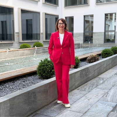 Claudia Kaufmann, Teilnehmerin des BTV Female Spirit, steht im Innenhof der BTV‑Filiale Innsbruck und trägt einen roten Hosenanzug.