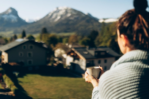 Eine Frau trinkt eine Tasse Kaffee und blickt gedankenverloren in die Ferne.