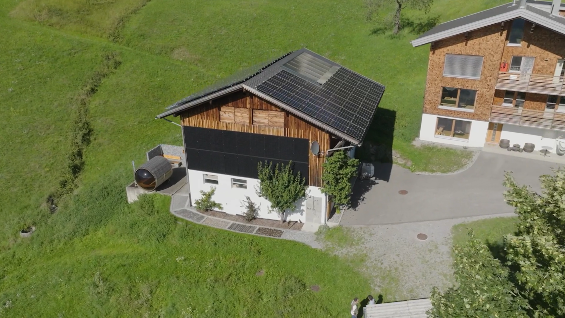 Ländlicher Bauernhof mit weitläufigem Gelände, auf dem eine moderne Saunanlage mit Holzfassade steht; umgeben von Wiesen, Bäumen und traditionellen Hofgebäuden.