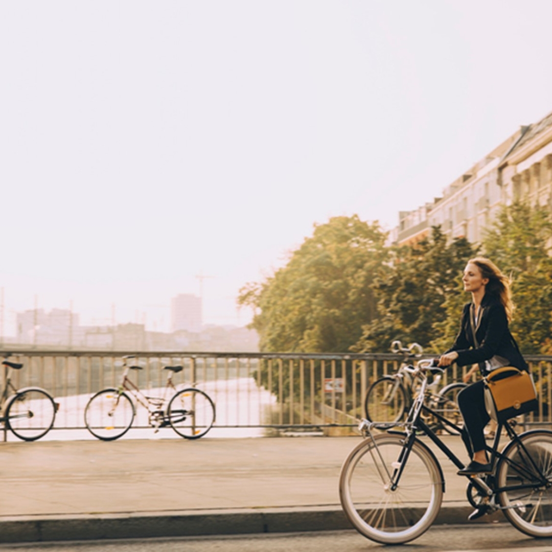 A woman rides a bike over a bridge in a city