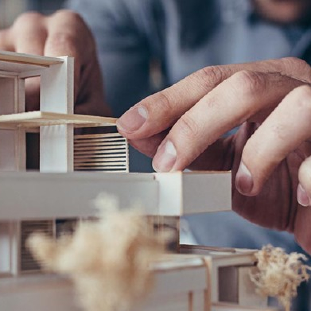 A person works on a wood house model