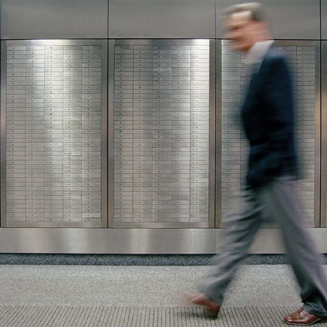 A business man walks by lockers in a bank institute