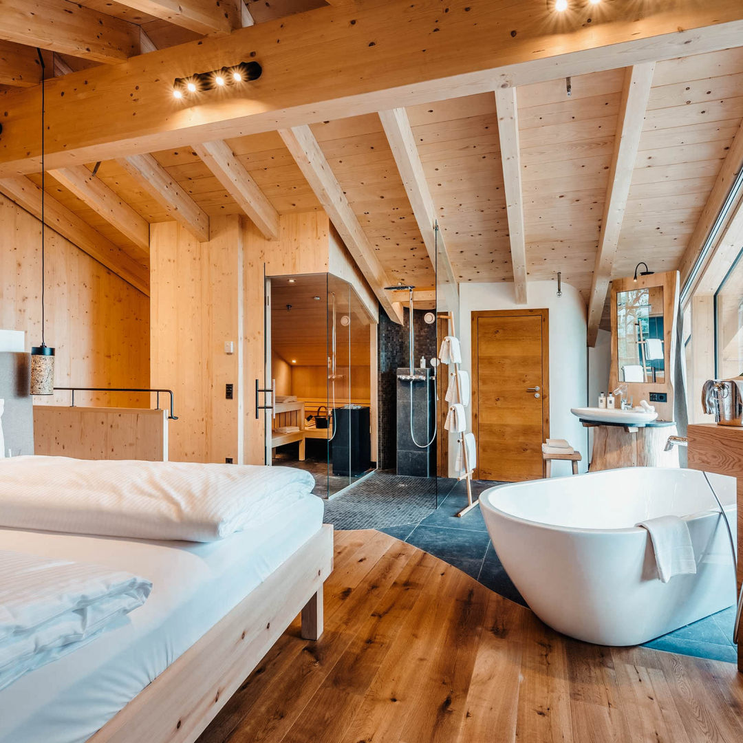 Hotelzimmer aus Holz mit Bett und freistehender Badewanne.